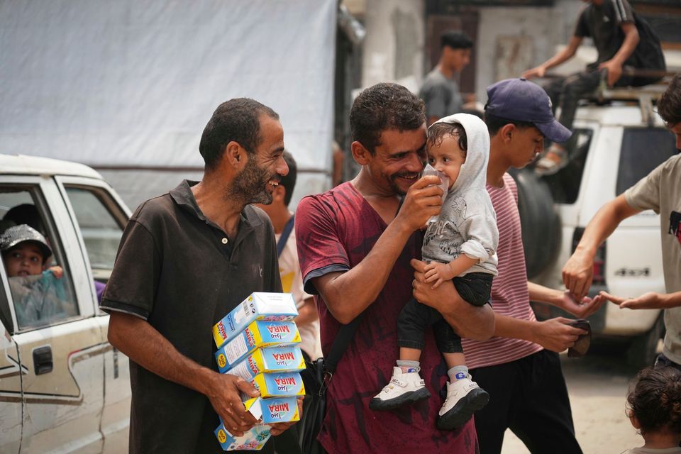 A man gives a child water from a plastic bag in Gaza City. Photo: AP